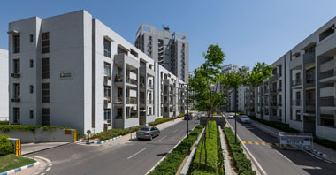 a roadside view of boulevard residences with boulevard heights in the background a project in vatika inxt by vatika group