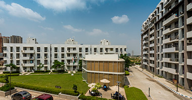 “a view of landscaped garden & buildings of vatika city homes in vatika inxt a project by vatika group